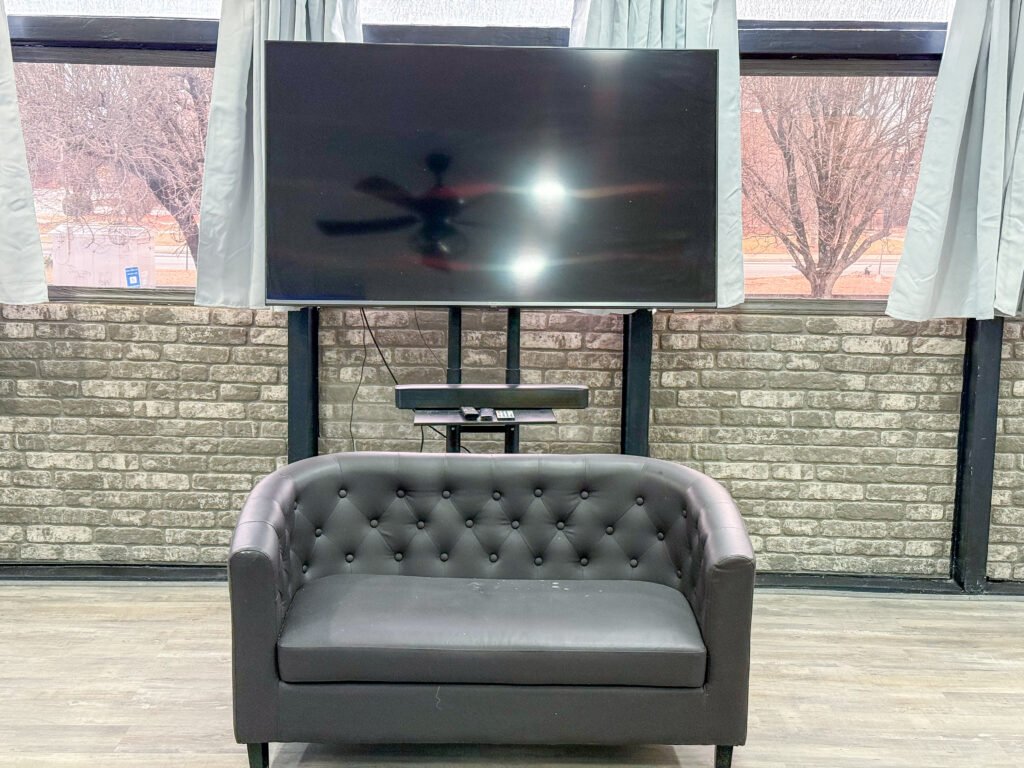 Lounge area with seating and wall-mounted television inside Unit 1 at The Flight Deck Residences.